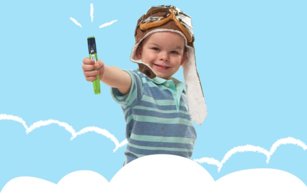 Four-year-old boy wearing an old fashioned, leather pilot&rsquo;s hat and goggles, smiling at camera and holding out a FlexPro&reg; pen.