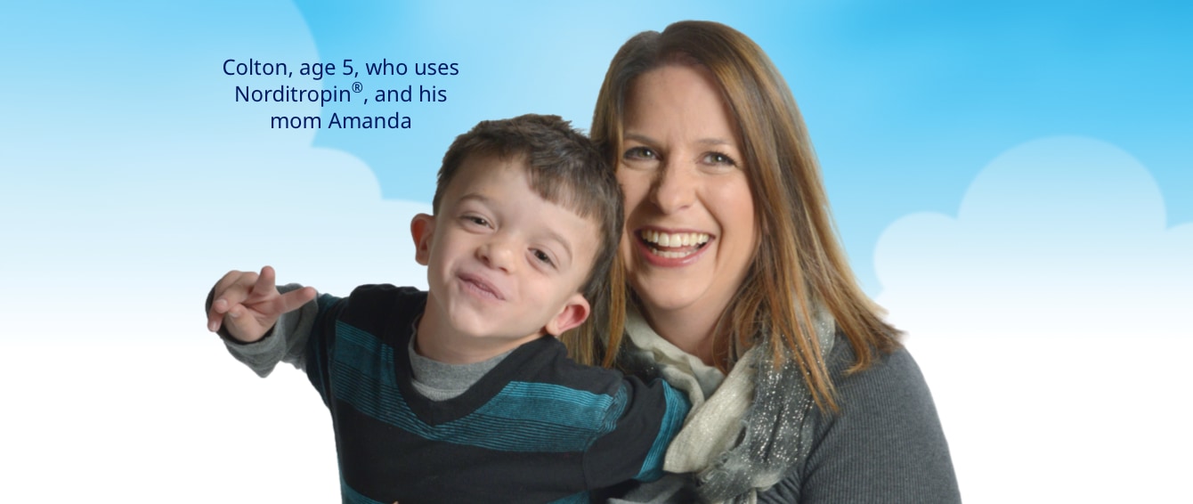 A photo of a mother, Amanda, holding her son, Colton, who is 5, on her lap. Amanda has long hair and is wearing a scarf; Colton is wearing a striped sweater. They are both smiling.