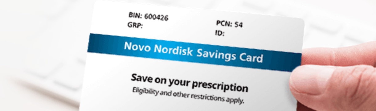 A closeup image of a hand holding a Novo Nordisk Savings Card. The card has a blue stripe, and includes the text, &lsquo;Save on your prescription.&rsquo;
