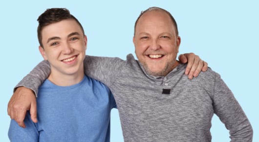 Photo of a young man and his father smiling into the camera.