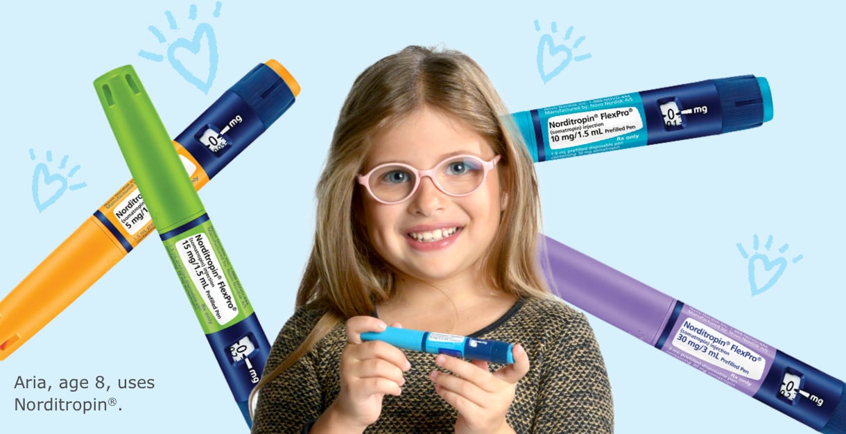 Photo of Aria, age 8, who uses Norditropin&reg;, holding a FlexPro&reg; pen with other pens in the background.